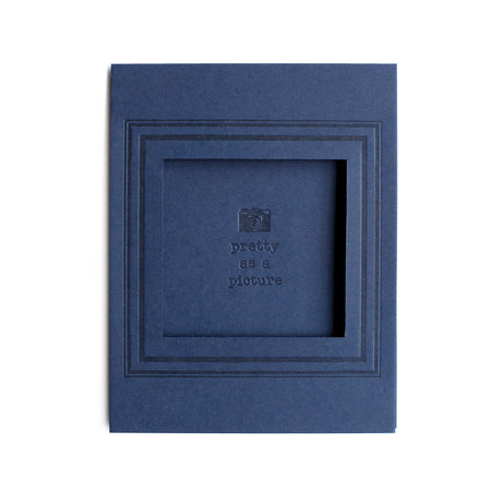 Rectangle blue card with arched photo cut out in center with text saying, “Pretty As A Picture” with an embossed image of a camera.  A matching envelope is included.