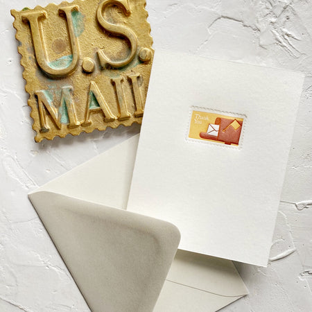 White card with image of a postage stamp with tan background and brown mailbox with a white envelope sticking out. White text saying, “Thank You”. A light gray envelope is included.