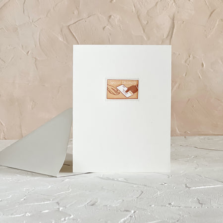 White card with an image of a postage stamp with tan background with image of two hands passing a mailing envelope. White text saying, “Special Delivery”. A gray envelope is included.