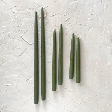 Tall skinny moss green colored tapered candles.
