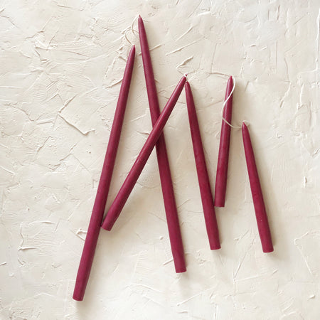 Tall skinny wine colored tapered candles.