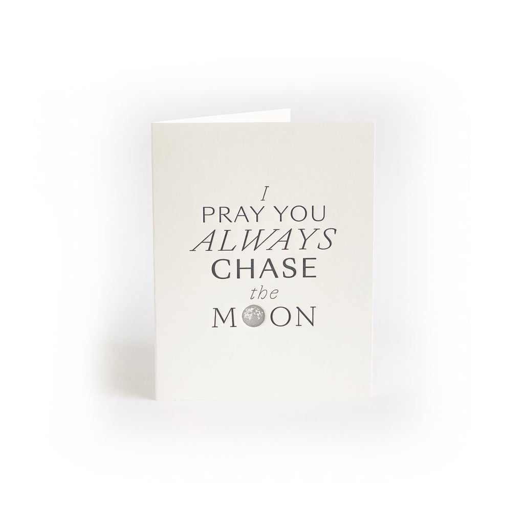 White card with gray text saying, “I Pray You Always Chase the Moon”. Image of a gray moon. A gray envelope is included.