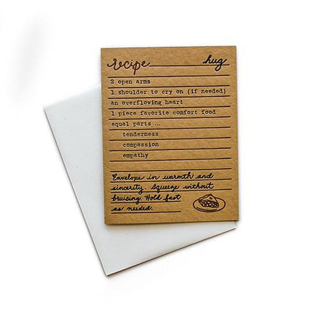 Brown card with black and brown text saying, “Recipe for Hug: 2 open arms; 1 shoulder to cry on; an overflowing heart; 1 piece of favorite comfort food; equal parts…tenderness; compassion; empathy. Envelope in warmth and sincerity. Squeeze without bruising. Hold fast as needed.” Image of slice of pie in bottom right corner. A white envelope is included.