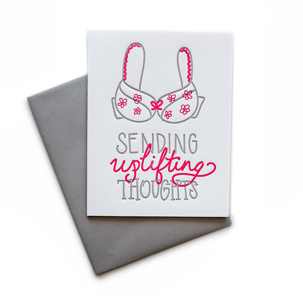 White card with gray and red text saying, “Sending Uplifting Thoughts”. Images of a gray and red flowered bra. A gray envelope is included.