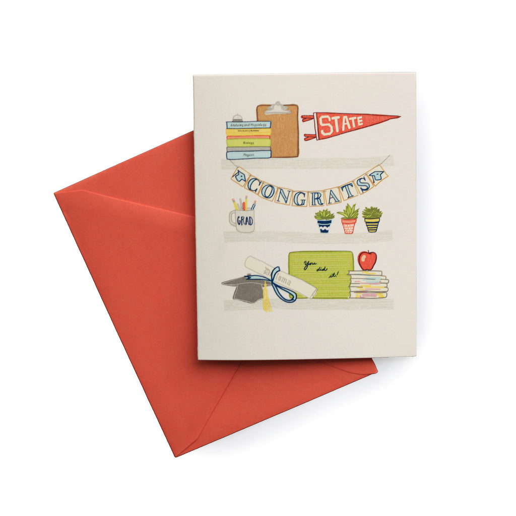 Ivory card with images of items for a graduation: books, clipboard, State college pennant flag; congrats banner; Grad mug with pens & pencils; potted plants; a graduation hat with diploma; stack of books with red apple on top. A red envelope is included.