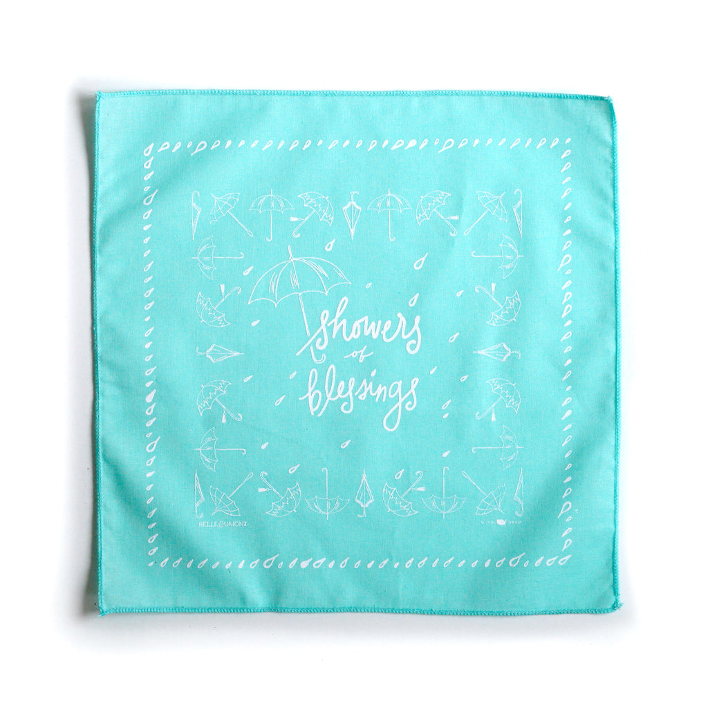 Teal square with white text saying, “Showers and Blessings” with images of umbrellas and raindrops.