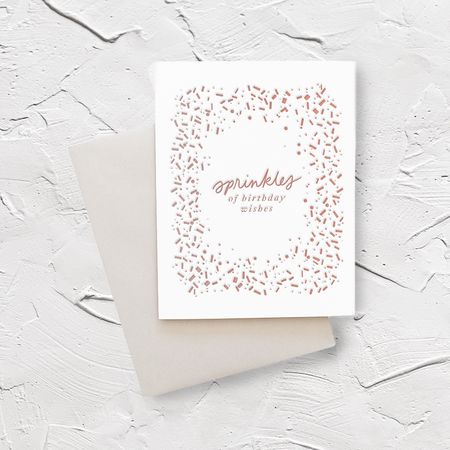 White card with red text saying, “Sprinkles of Birthday Wishes”. Images of red and gray sprinkles scattered around card. A gray envelope is included.