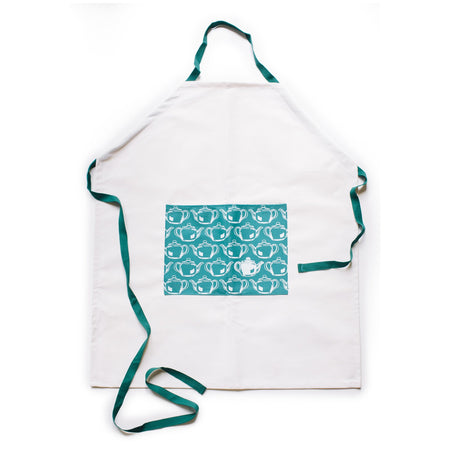 White apron with a teal rectangle in the middle with images of tiled white teapots. Teal straps for around neck and waist.