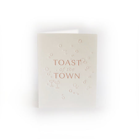 Ivory card with brown text saying, “Toast of the Town”. Images of embossed champagne glasses and bubbles. A gray envelope is included.