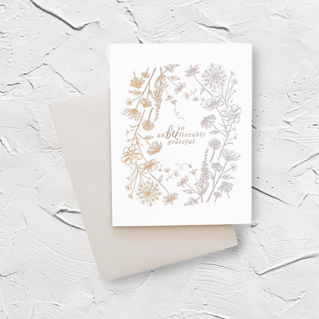 White card with brown text saying, “So Unbeelievably Grateful”. Images of flowers and bees. A gray envelope is included.