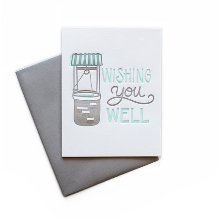 White card with gray and teal text saying, “Wishing You Well”. Image of a gray and teal wishing well. A gray envelope is included.