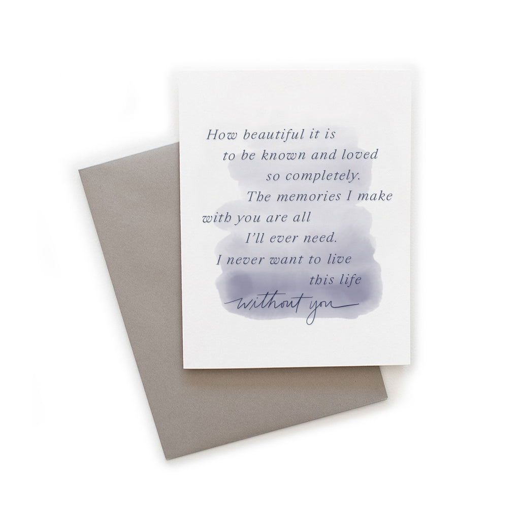 White card with watercolor wash background in blue tones with blue text saying, “How beautiful it is to be known and loved so completely. The memories I make with you are all I’ll ever need. I never want to live this life without you.” A gray envelope is included.