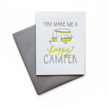 White card with gray and yellow text saying, “You Make Me A Happy Camper”. Image of a yellow vintage camper. A gray envelope is included.