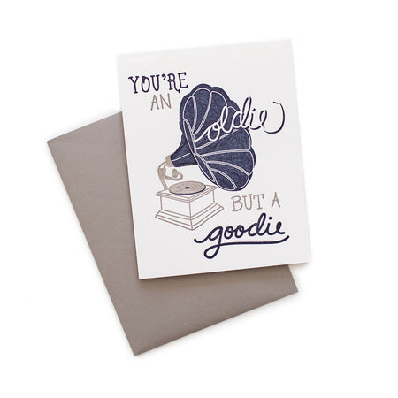 White card with gray and blue text saying, “You’re An Oldie But Goodie”. Image of a blue and gray phonograph vintage record player. A gray envelope is included.