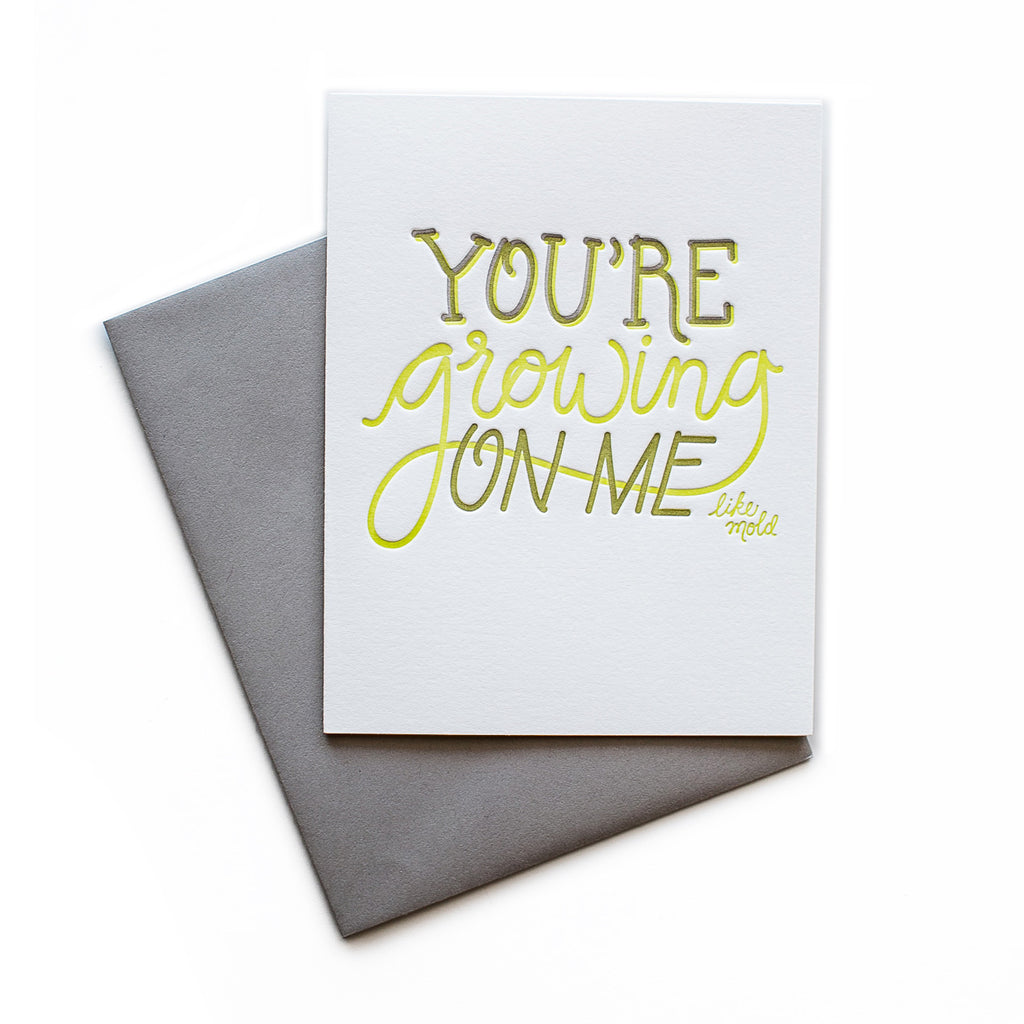 White card with gray and yellow text saying, “You’re Growing On Me Like Mold”. A gray envelope is included.
