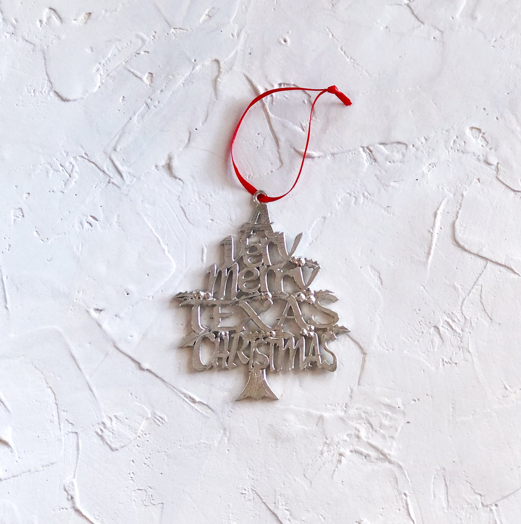 Silver pewter ornament with text saying, “A Very Merry Texas Christmas” shaped into the image of a Christmas tree.