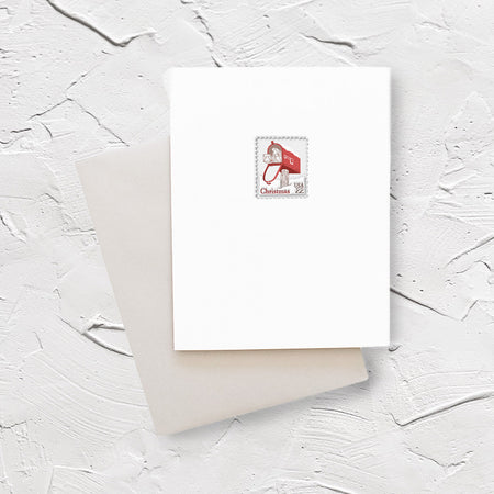 White card with image of a postage stamp with a red mailbox with packages poking out. Red text saying, “Christmas” and black text saying, “US22”. An ivory envelope is included.