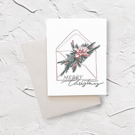 White card with green text saying, “Merry Christmas”. Images of a white mailing envelope with pine tree greenery and red poinsettia flower coming out of the flap. An ivory envelope is included.