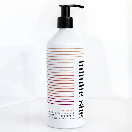 White bottle with black pump top and black text saying, “Infinite She Vibrant Hydrating Body Lotion”. Images of yellow, brown, and purple lined design.