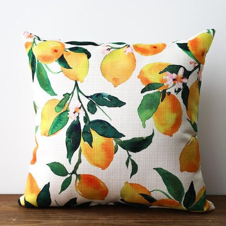 Square white pillow with images of yellow lemons and green leaves.