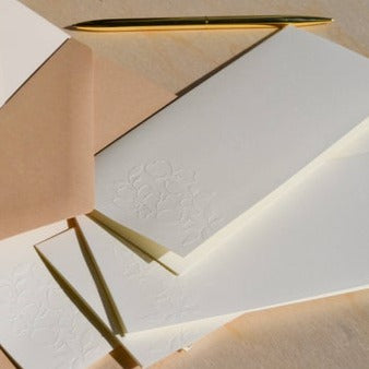 Ivory notecards with embossed floral pattern across bottom of card. Brown envelopes included.