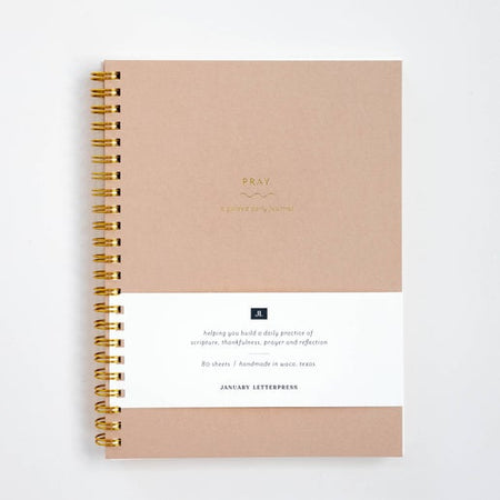 Blush pink cover with gold foil text saying, “Pray A Guided Daily Journal”. Gold coil binding on left side.