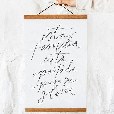 Print on white background with wood slat on top and bottom with black text saying, “Esta Familia Esta Apartada Para Su Gloria”.